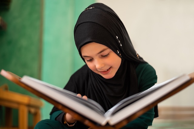 A Muslim girl reading a holy book Quran inside the mosque.